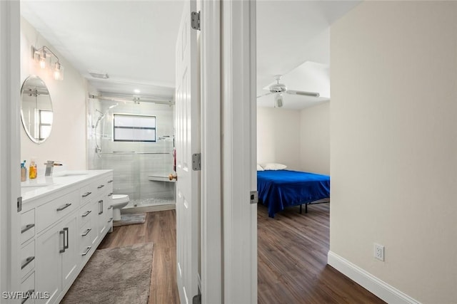 bathroom with ceiling fan, hardwood / wood-style floors, vanity, toilet, and walk in shower