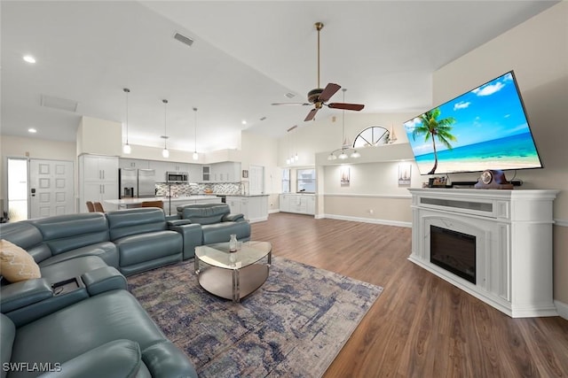 living room featuring hardwood / wood-style flooring, ceiling fan, and high vaulted ceiling