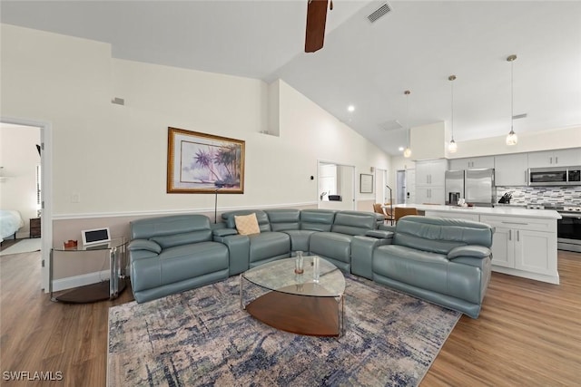 living room featuring light hardwood / wood-style flooring and high vaulted ceiling