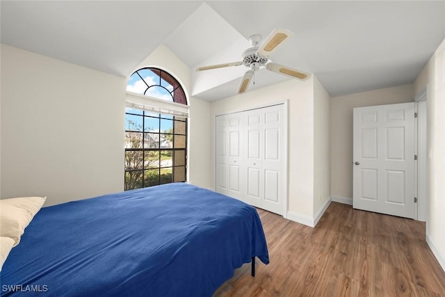 bedroom with vaulted ceiling, dark wood-type flooring, ceiling fan, and a closet