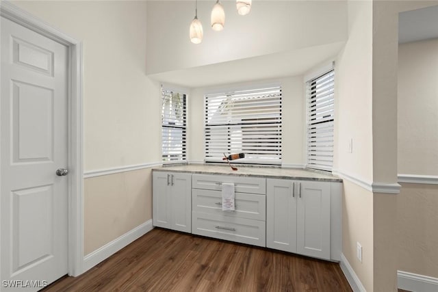 kitchen featuring hanging light fixtures, white cabinetry, light stone countertops, and dark wood-type flooring