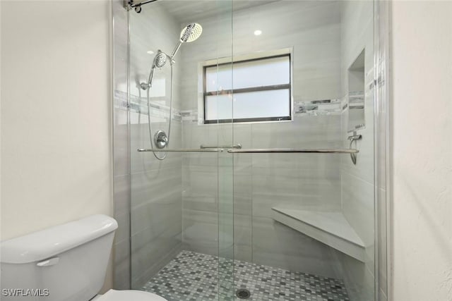 bathroom with a shower with shower door and toilet