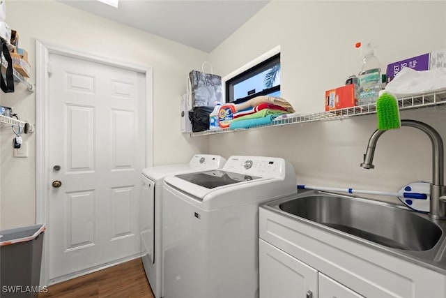 laundry area featuring sink, dark hardwood / wood-style floors, cabinets, and washing machine and clothes dryer