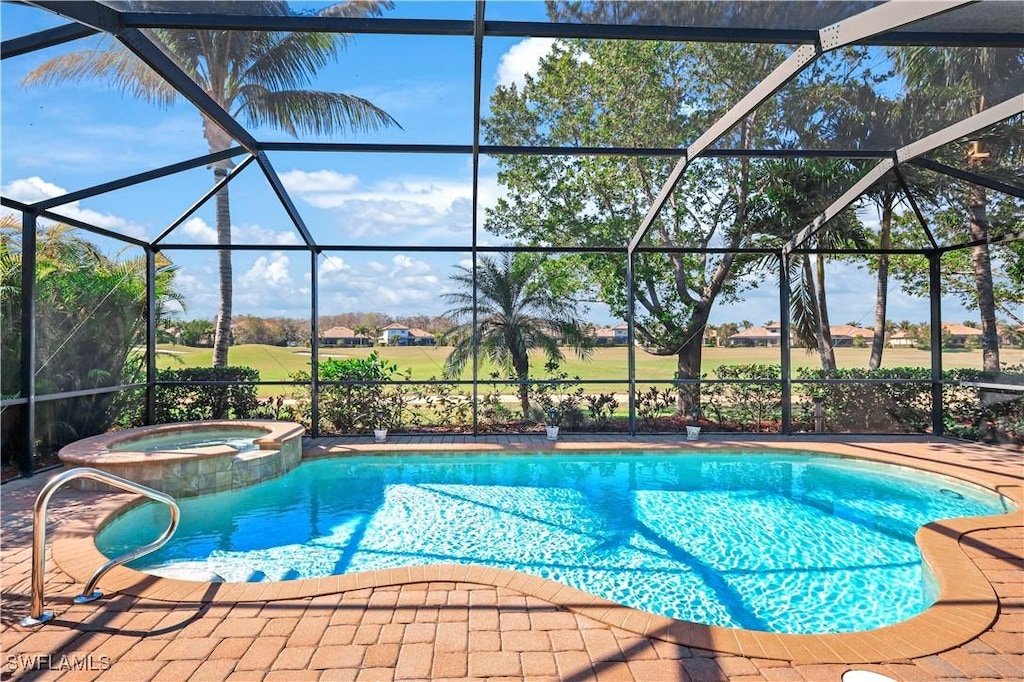 view of pool featuring an in ground hot tub, glass enclosure, and a patio area