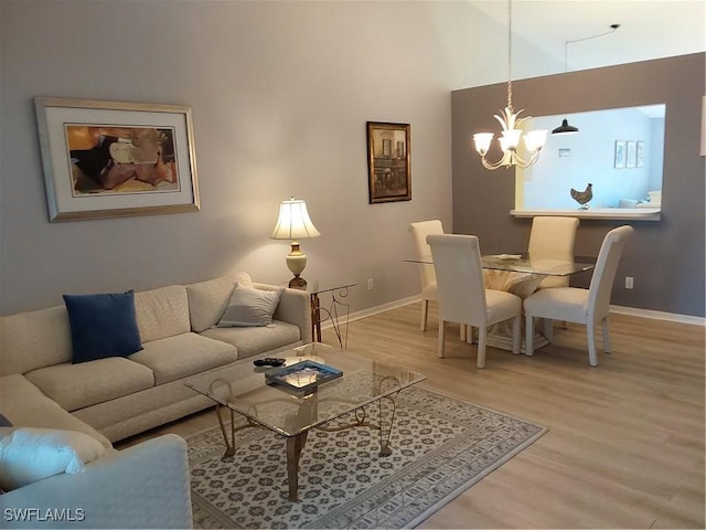 living room with an inviting chandelier, a high ceiling, and light wood-type flooring