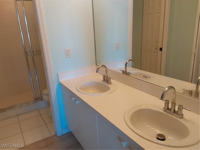 bathroom featuring a shower with door, vanity, tile patterned flooring, and toilet