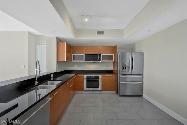 kitchen featuring light tile patterned flooring, rail lighting, sink, appliances with stainless steel finishes, and a raised ceiling