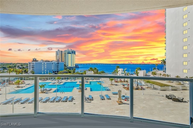 balcony at dusk featuring a water view