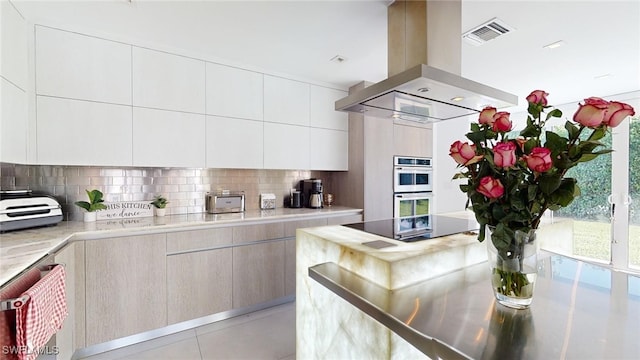 kitchen featuring backsplash, island exhaust hood, plenty of natural light, stainless steel double oven, and black electric cooktop