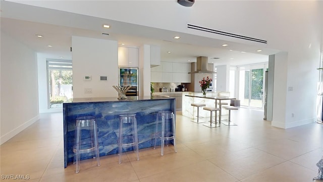 kitchen with white cabinetry, a healthy amount of sunlight, island range hood, and a breakfast bar