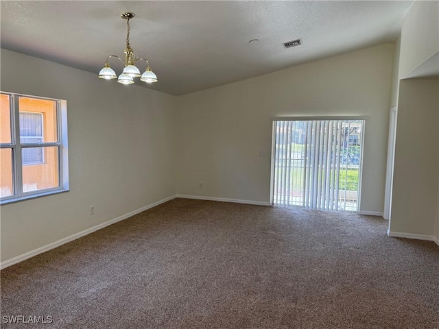 spare room featuring lofted ceiling, carpet, and a chandelier