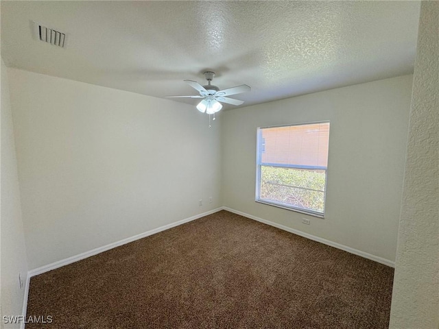 unfurnished room with ceiling fan, a textured ceiling, and dark carpet