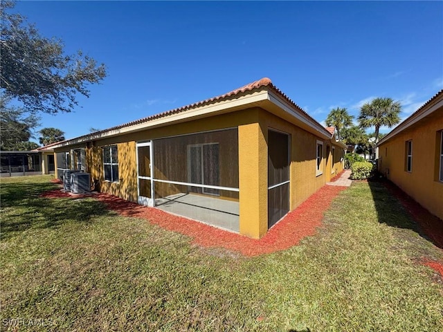 back of property featuring a sunroom and a lawn