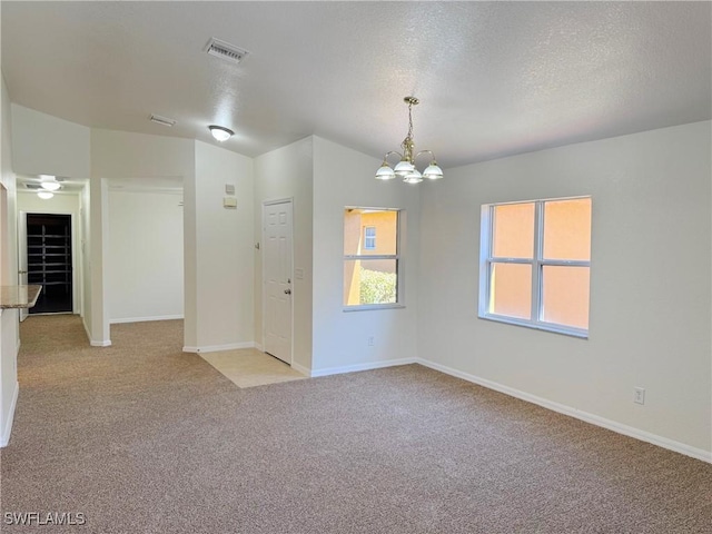 empty room featuring light carpet, a notable chandelier, and a textured ceiling