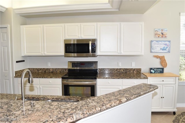 kitchen with light stone countertops, white cabinetry, appliances with stainless steel finishes, and sink