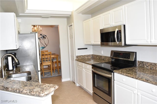 kitchen with white cabinetry, appliances with stainless steel finishes, sink, and dark stone countertops