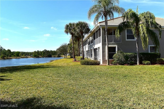 view of yard with a sunroom and a water view