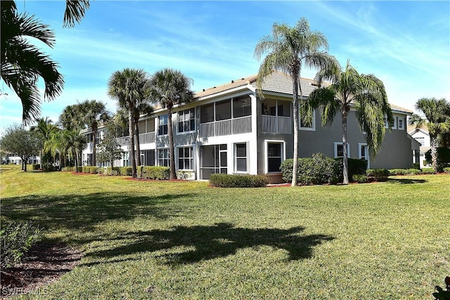 back of property with a sunroom and a lawn