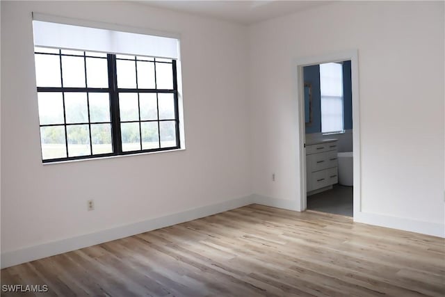 unfurnished bedroom featuring connected bathroom and light wood-type flooring