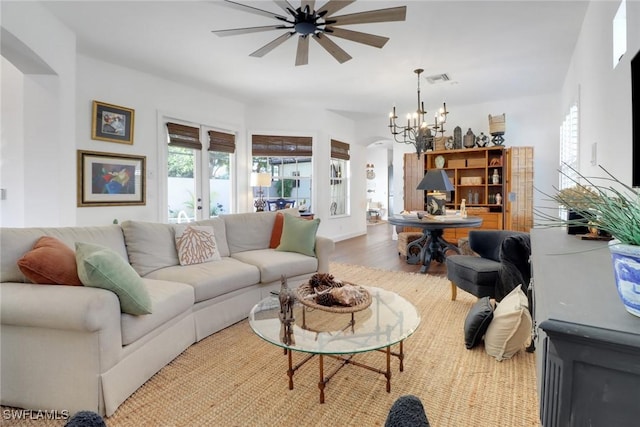 living room featuring ceiling fan with notable chandelier and wood-type flooring