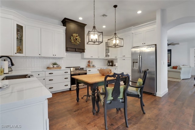 kitchen with pendant lighting, sink, stainless steel appliances, light stone counters, and white cabinets