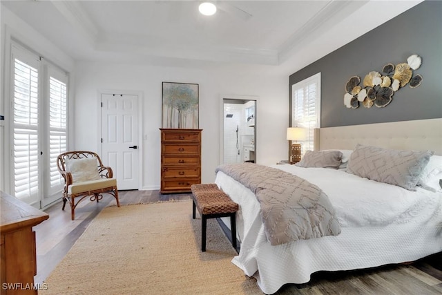 bedroom featuring a raised ceiling, ensuite bathroom, hardwood / wood-style flooring, and ceiling fan