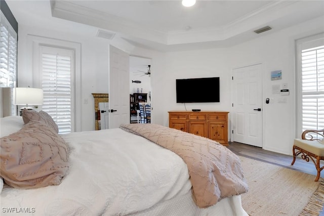 bedroom with crown molding, a tray ceiling, and hardwood / wood-style flooring