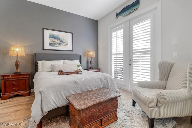 bedroom with multiple windows, access to outside, and light wood-type flooring