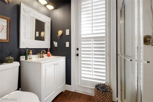 bathroom with hardwood / wood-style flooring, vanity, a shower with door, and toilet