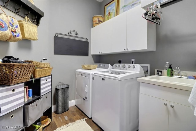 clothes washing area featuring cabinets, wood-type flooring, separate washer and dryer, and sink