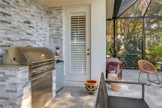 view of patio / terrace with area for grilling, a lanai, and exterior kitchen