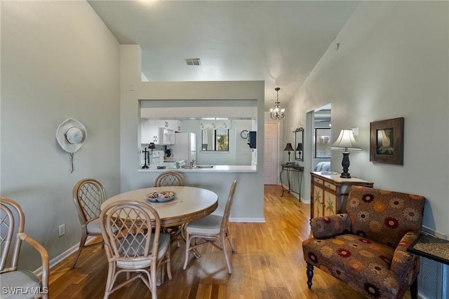 dining space with a notable chandelier and light hardwood / wood-style floors