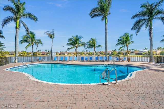 pool with a water view, a patio area, and fence