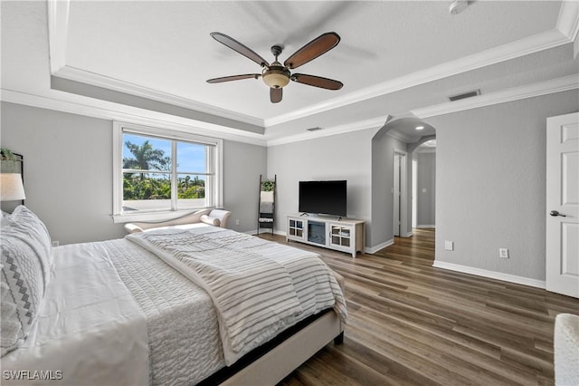 bedroom featuring crown molding, a tray ceiling, wood finished floors, and visible vents