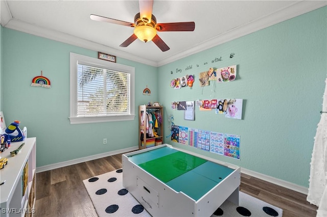 playroom with ornamental molding, ceiling fan, and dark hardwood / wood-style flooring