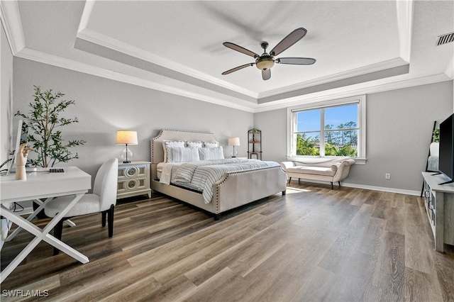 bedroom with a raised ceiling, wood-type flooring, ornamental molding, and ceiling fan