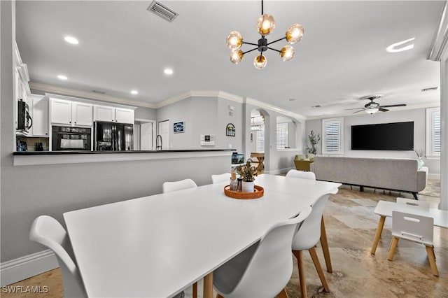 dining room with baseboards, ornamental molding, visible vents, arched walkways, and ceiling fan with notable chandelier