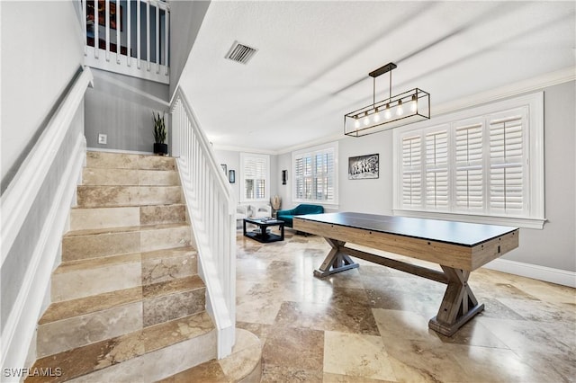 recreation room featuring crown molding, visible vents, baseboards, and stone tile flooring