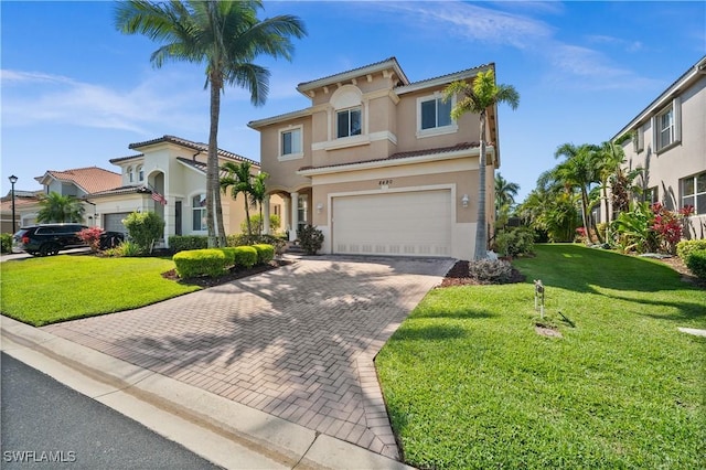 mediterranean / spanish-style house featuring a garage, stucco siding, a front lawn, and decorative driveway