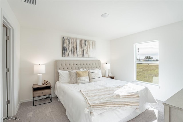 bedroom with baseboards, visible vents, and light colored carpet