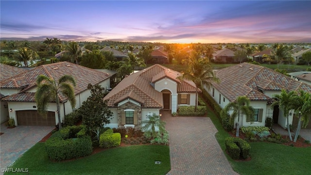 view of front of property with a tile roof, a front yard, decorative driveway, and stucco siding