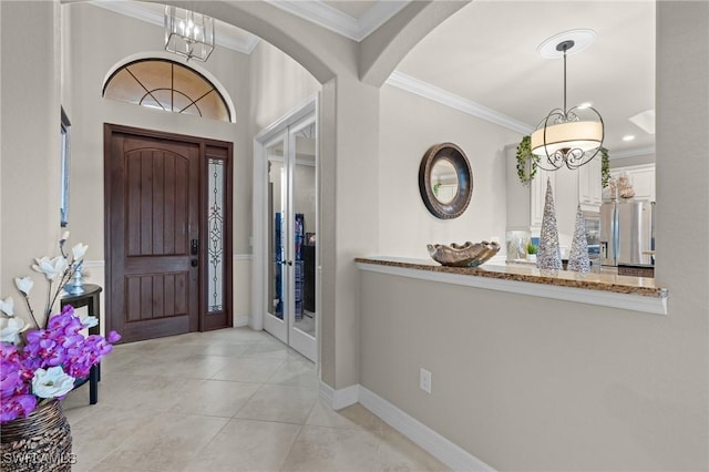 entryway with tile patterned flooring, crown molding, arched walkways, and baseboards