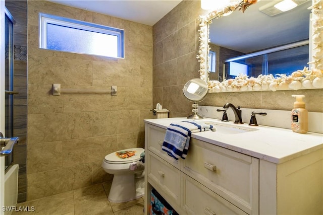 bathroom with tile patterned flooring, vanity, tile walls, and toilet