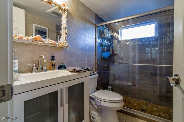 bathroom with tile walls, decorative backsplash, vanity, toilet, and a shower with door