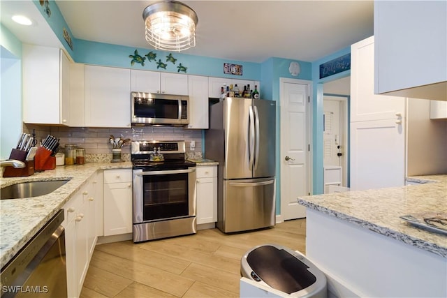 kitchen with light stone counters, stainless steel appliances, sink, and white cabinets