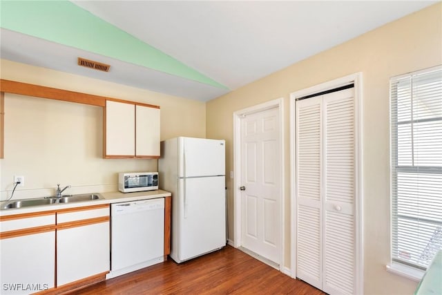 kitchen featuring sink, white appliances, white cabinetry, vaulted ceiling, and light wood-type flooring