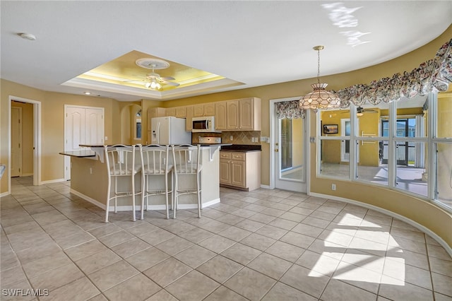 kitchen featuring pendant lighting, white appliances, ceiling fan, a tray ceiling, and a kitchen island