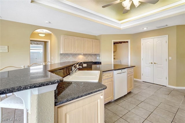 kitchen featuring tasteful backsplash, sink, white dishwasher, a tray ceiling, and crown molding