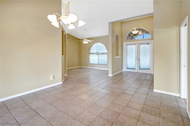 foyer entrance featuring light tile patterned floors, ceiling fan with notable chandelier, high vaulted ceiling, and french doors