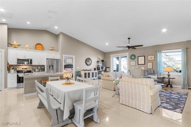 tiled dining space featuring ceiling fan, plenty of natural light, and high vaulted ceiling